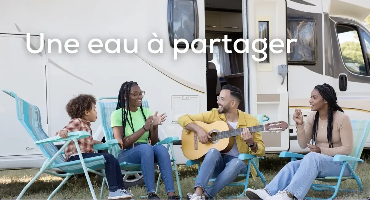 Un groupe de campeurs partage un moment convivial devant son camping-car — une eau à partager